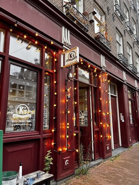 K&rsquo;s, a deep-red shopfront strung with lights in Amsterdam.